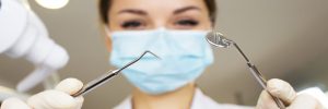 female-dentist-close-up-holder-dental-tools-with-medical-mask