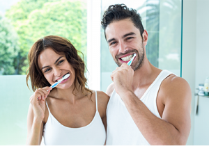 man-and-woman-brushing-their-teeth